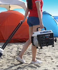Person carrying Portable Gas Powered Generator With Carrying Handle 1200W Peak 900W Running 2 Stroke Recoil Start Compact Durable Design For Camping And Outdoor Use One Point One Gallon Fuel Tank Delivers Up To Five Hours At Half Load Black And White on sandy beach near tents.
