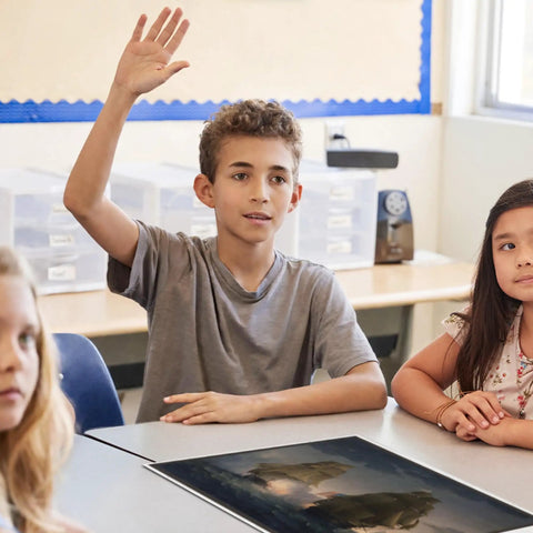 Student raising hand in social studies class with 10 Poster Set Of American War Paintings For Social Studies Classrooms And K-12 Teachers, 12 X 18 Inch History Posters, Learning Materials For US History Made In USA on table.