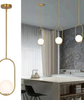 Gold Globe Pendant Light Fixture With Adjustable Hanging Length, Modern Mid Century Chandelier in brushed brass finish over kitchen island.