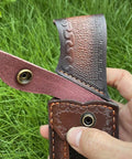 Close-up of rugged leather knife sheath for fixed blade with secure buckle and intricate stitching design.