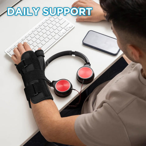 Man wearing Carpal Tunnel Night Wrist Brace with Adjustable Fit and Four Splints for arthritis and tendonitis at a desk.