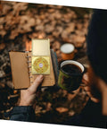 Person holding Small 10cm Alloy Feng Shui Compass With Flip Cover, Waterproof Outdoor Navigation Tool and a notebook outdoors