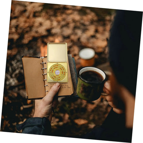 Person holding Small 10cm Alloy Feng Shui Compass With Flip Cover, Waterproof Outdoor Navigation Tool and a notebook outdoors