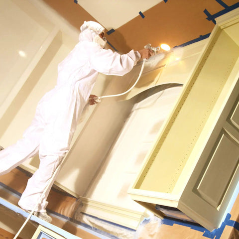 Painter using sprayer with brown general purpose masking paper 12 in x 180 ft for painting trim windows and doors.