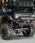 Front And Rear Aluminum Tube Bumper Set For 1/18 TRX4M Bronco Crawler Lightweight Metal Armor With LED Front Bumper For Night Drives Removable Tow Hitch On Rear No Mods Required Fits Stock Body installed on black TRX4M Bronco model, showing LED lights.