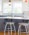 Modern kitchen with island and chrome bar stools under pendant lighting, hardwood floor, and large windows