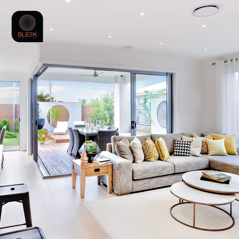 Modern living room with open sliding doors to terrace, featuring neutral colors, gray sofa, and stylish decor.