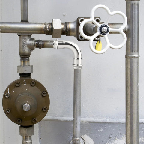 Front view: stainless steel 1-inch 90-degree press elbow in a metal plumbing line with a white-handled gate valve