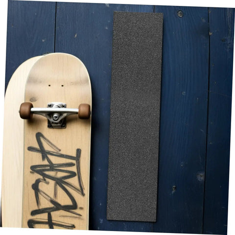 Two Pack Black PVC Grip Tape Sheets For Skateboard And Scooter Decks Weatherproof No Slip Traction Tape next to a skateboard.