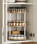 Three Tier Lazy Susan Rotating Spice Rack Featuring Smooth Ball Bearing Turntable System For Hassle Free Pantry Access White Natural Wood Countertop Organizer with spices inside a cabinet.
