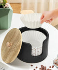 Coffee Filter Holder And Countertop Storage Jar With Lid, open with hand placing filter, wooden lid beside, for coffee station