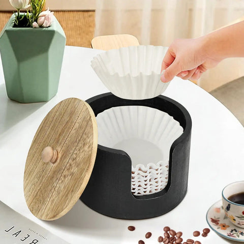 Coffee Filter Holder And Countertop Storage Jar With Lid, open with hand placing filter, wooden lid beside, for coffee station