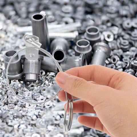 Hand holding Stainless Steel Quick Release Safety Pins With 240mm Coil Lanyard among pile of metal fasteners