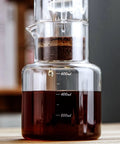 Premium Glass Cold Brew Drip Tower With Adjustable Flow Dripper For Smooth Cold Extraction Coffee Maker 600 Milliliter Gray Body brewing coffee with visible coffee grounds and liquid.