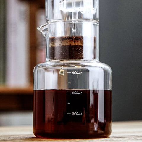 Premium Glass Cold Brew Drip Tower With Adjustable Flow Dripper For Smooth Cold Extraction Coffee Maker 600 Milliliter Gray Body brewing coffee with visible coffee grounds and liquid.
