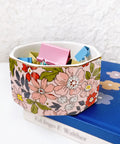 Ceramic Paper Clip Holder With Gold Line Dispenser, Desk Organizer For Paper Clips, floral pattern on desk next to blue book