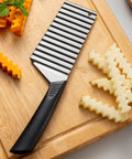 HAKIDZEL Wave potato cutter crinkle slicer with stainless steel blade and black handle on a wooden cutting board