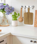 Acacia wood cutting boards set, 15-pack, hanging on kitchen wall hooks.