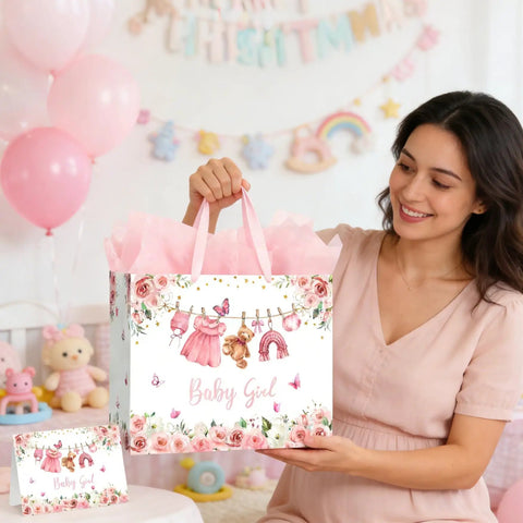 13 Inch Pink Floral Baby Gift Bag With Sturdy Handles Includes Matching Card And Three Sheets Of Tissue Paper The Perfect Gift Bag For Girl Baby Showers And Kiddo Birthday Parties held by a woman in a nursery setting.