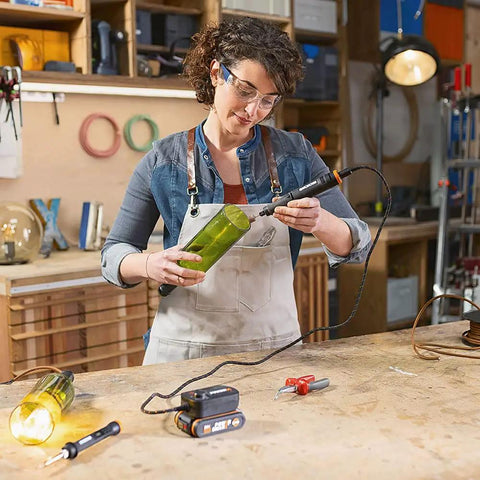 Woman using Top Tier Cordless Pen Engraver And Digital Soldering Iron Kit With Sweet 20V Battery on green bottle.