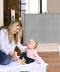 Mother with baby beside Retractable Baby Gate For Stairs And Doorways, 33 Inch Tall, Expands To 55 Inch Wide, Double Locking Safety gate.