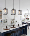 Rock Solid Black Pendant Lights For Kitchen Island, 3 Pack Sleek Industrial Farmhouse Lanterns With Adjustable Height and Clear Glass Shade above a modern kitchen island.