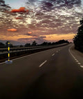 Heavy Duty Elastic Warning Bollard Post With Rock Solid Bounce Back Shield positioned on an empty road at sunset.
