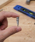 Hand holding a piece from the Heavy Duty Zinc Alloy Drywall Anchor Kit With Self Drilling Screws 30 Pack for mounting on walls