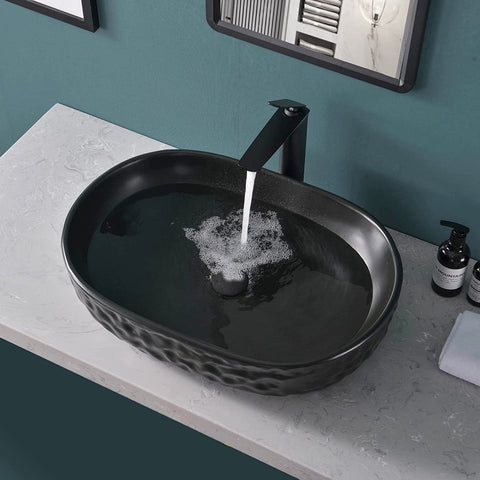Matte Black Oval Vessel Sink 23.5 By 15.7 Inches, Ceramic Countertop Bathroom Basin With Pop Up Drain, water flowing into sink