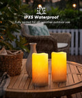 Lit Outdoor Solar Pillar Candles 3x6 Inches Waterproof Rechargeable Flameless Flickering Lights on outdoor table in rain