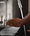 Moen Swyre Pulldown Kitchen Faucet, Chrome, 87508EW with hands demonstrating hands-free activation feature.