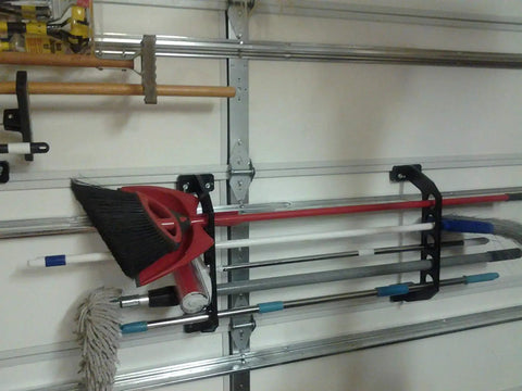 Garage Door Organizer Rack for Fishing Gear and Tools 18 Inch ABS Plastic Rod Holder mounted on a garage door with brooms and tools