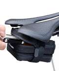 Cyclist placing tool into Rear Saddle Bag Organizer for Bike Touring and Bikepacking, Waterproof Split Seat Pack under seat.