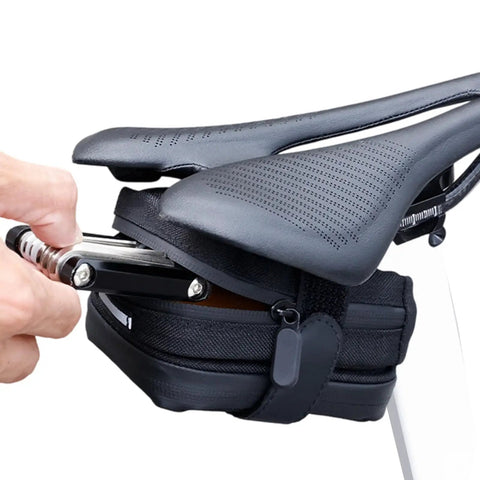 Cyclist placing tool into Rear Saddle Bag Organizer for Bike Touring and Bikepacking, Waterproof Split Seat Pack under seat.