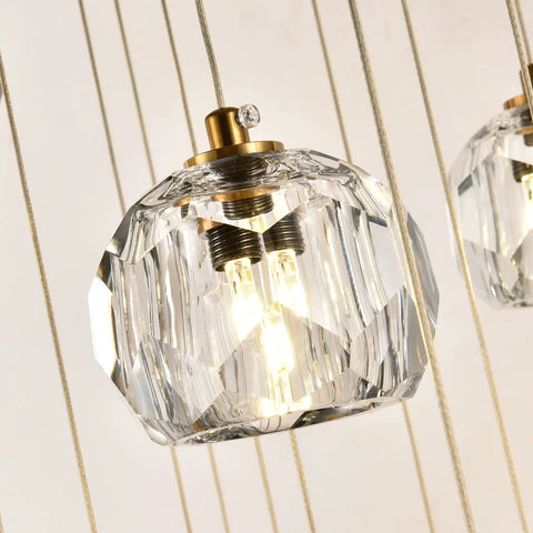 Close-up of Modern Raindrop Pendant Lights Set Of 3, featuring brass round hanging lamps with clear crystal prisms, lit bulbs visible