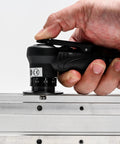 Mini chamfering tool side view, Amazon black handheld pneumatic beveler with depth dial beveling a metal rail.