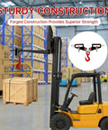 Heavy Duty Twin Forklift Lifting Hooks Featuring Bold Swivel Heads and Tight Mounting Bolts for Standard Tractor or Garage Forks No Fuss Setup solidly lifting a wooden crate in a warehouse.