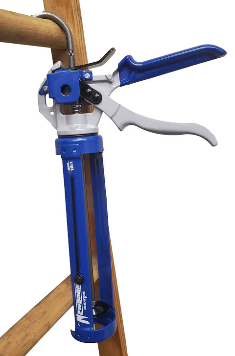 Pro Grade Caulking Gun With 18 To 1 Thrust, Revolving Barrel, Smooth Zinc Alloy Handle, One-Tenth Gallon Cartridge shown on wooden frame