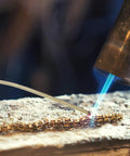 Top Tier Copper Welding Rods Kit 4pcs For Jewelry Making, using a torch to solder golden metal sticks on a workbench.