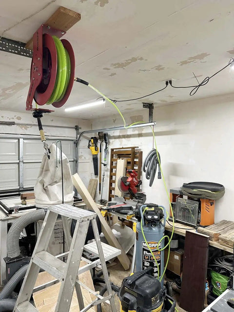 Reinforced Polyurethane 3/8 Inch ID Air Hose, 100 Ft, 300 PSI, mounted on reel in woodworking shop with high flow quick coupler.