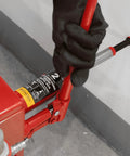Torin red 2-ton welded car bottle jack side view with black-gloved hand inserting the handle.