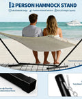 12 Ft Hammock Stand With Hooks And Chains For Two Beefy Heavy Duty Steel Frame For Outdoor Patio Backyard Portable Black Design Supports Up To 450 Pounds shown with two people on a beach.