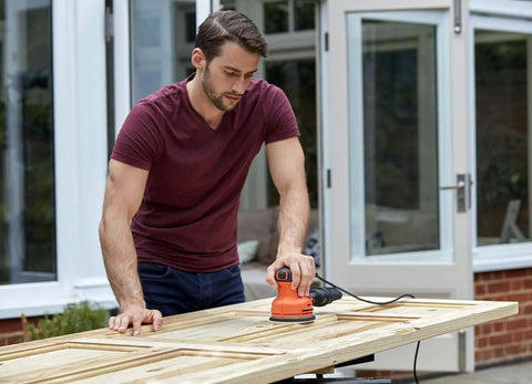 Man using Pro Level Random Orbital Finisher Sander on wooden surface for fast sanding and smoothing.