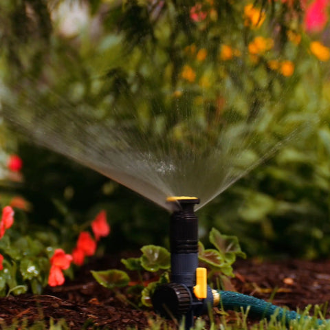 Three Pack Multi Adjustable Spike Sprinklers With Quick Connect Bundle in use on a garden bed, black grey yellow, hose ready.