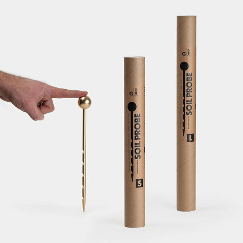 Hand holding Unlimited Brass Soil Probe With Moisture Meter And Sampler No Batteries Required Root Aerator And Plant Water Monitor For Pots And Indoor Gardens For Potted Plants And Home Gardeners near boxed probe