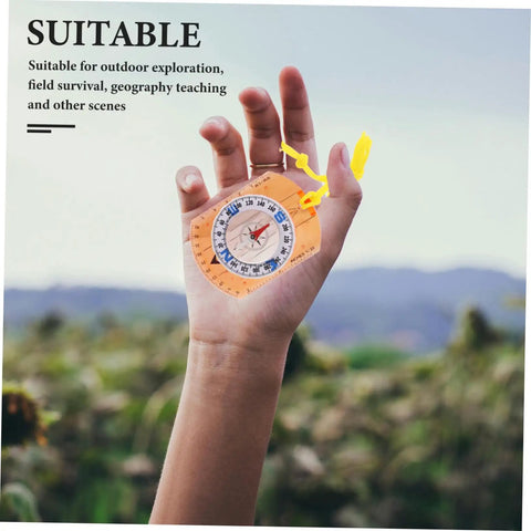 Hand holding orienteering compass with luminous pointer and ruler for hiking camping and backpacking acrylic outdoor tool.