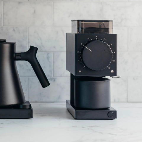 64mm Flat Burr Electric Coffee Grinder Built For Brewed Coffee Lovers With 31 Grind Settings next to pour-over kettle on counter.