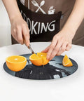 Person slicing orange on Death Scythe Round Tempered Glass Cutting Board With Non-Slip Rubber Feet, Small 7.9 By 7.9 Inches