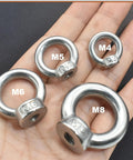 Hand holding M4, M5, M6, M8 lifting eye nuts in varying sizes with clear markings on a black background