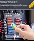 Hand holding a green and yellow mini blade fuse above a fuse box in a vehicle from the Heavy Duty Mini Blade Fuse Assortment Kit With Puller.
